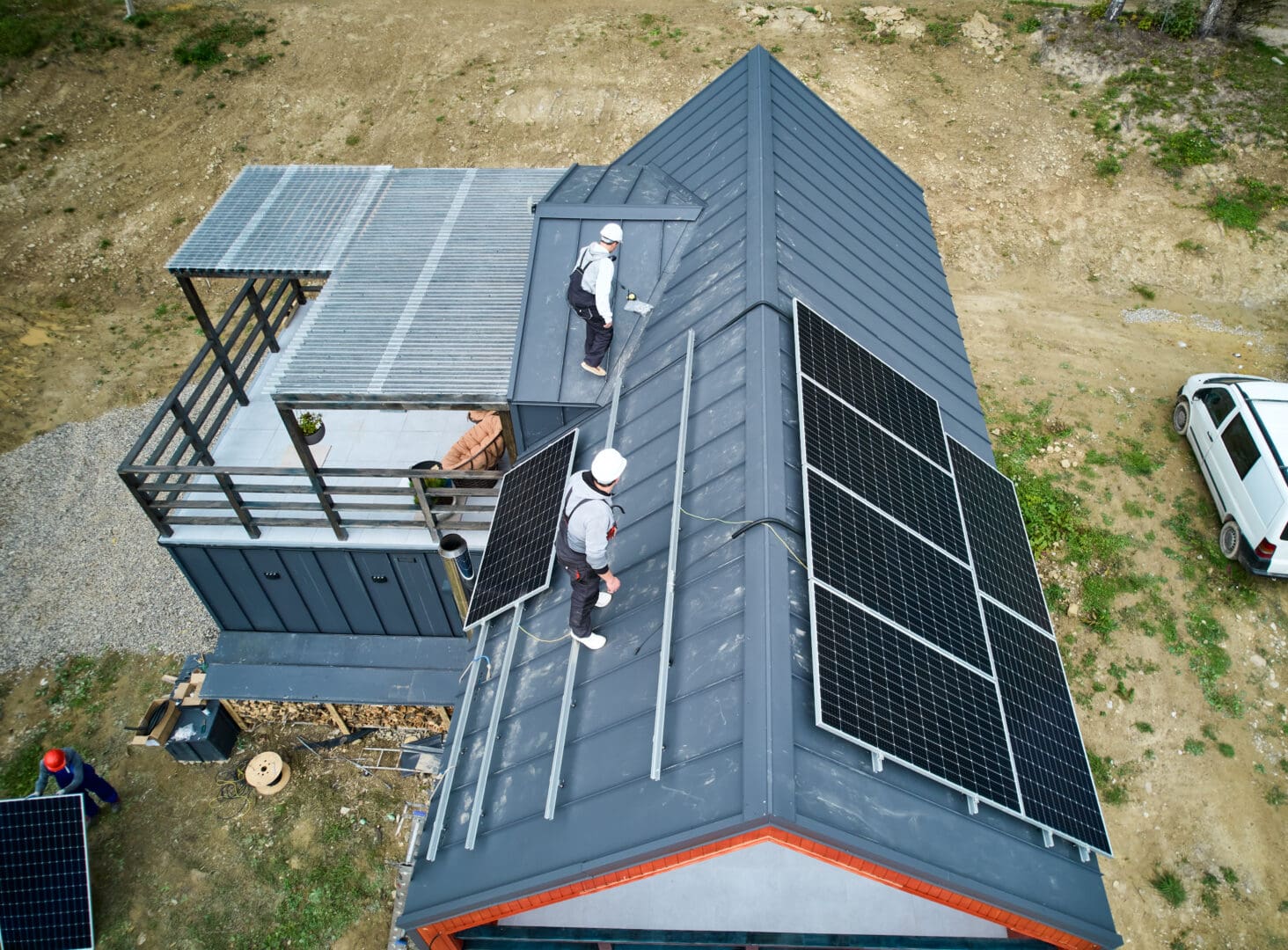 Well Mitigation Men workers preparing for mounting photovoltaic solar modules on roof of house. Electricians in helmets installing solar panel system outdoors. Concept of alternative and renewable energy.